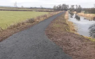 new towpath surface on the left with canal on the right fields in the background