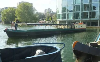 Empty trip boat moves passed moored boats in Islington City Rd Basin