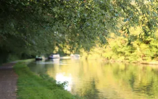 View round a bend on Market Harborough Arm of Grand Union Canal with moored boats in background