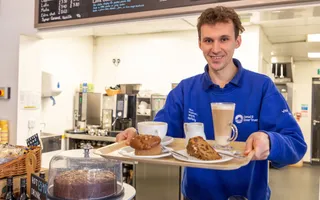 Man holding tray of cake and coffee