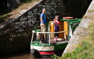 A man and a girl on board a boat waving at the camera