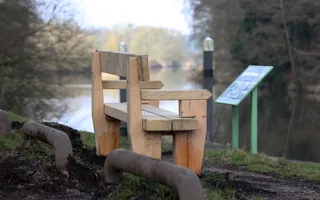 A wooden bench is positioned looking out over the canal