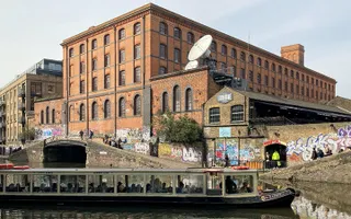 A bridge and tunnel on the canal in front of a large brick building