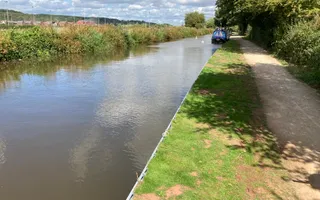 A flat gravel towpath with a grass bank runs alongside the canal