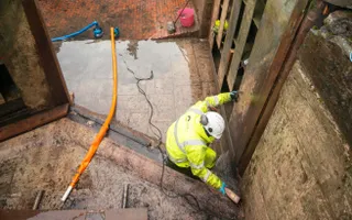 Worker in high vis and hard hat in the bottom of a canal