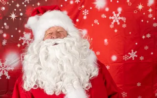 Santa posing for photo infrom of snow flakes