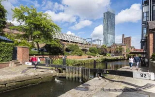 Person sits on a lock gate in the sun on the Rochdale Canal in Manchester