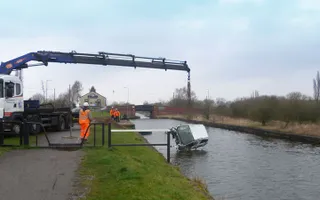 A crane pulling a car out of the canal