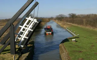 Open lift bridge on Northampton Arm of Grand Union Canal with boat behind