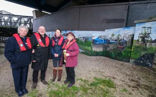 4 people in lifejackets standing infrom of mural