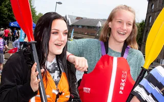 Two teenage girls hold up canoe paddles