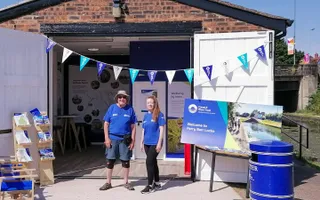 Two Canal & River Trust workers stand at a welcome station at Perry Barr