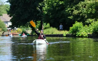 girl canoeing on leafy canal