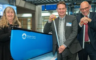 A woman and two men in smart clothing leaning on a boat