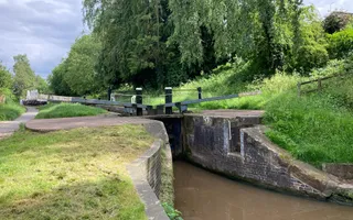 A lock gate with a canal running below it and grassy verges to either side.