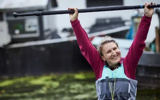 Female paddler smiling and holding up her paddle