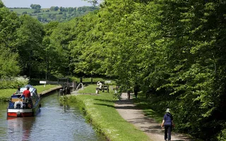 Boat entering lock on Peak Forest Canal with walkers on the towpath