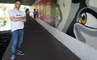 A man in a white t-shirt looks on standing next to canalside murals