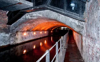 Picture of a dark tunnel with a canal running through it