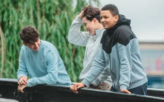 Three teenage boys chatting to each other on a bridge