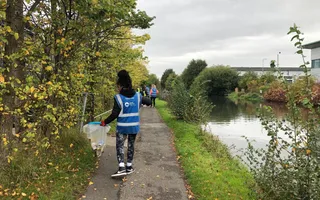Volunteer on a towpath picking up litter alongside a canal