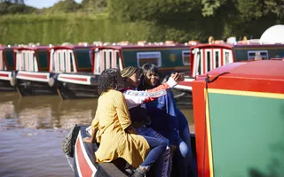 Three woman sit near the front of the boat, smiling into a camera phone for a selfie