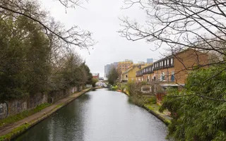 A row of houses back onto a canal as it travels away from camera towards a misty skyline.