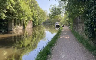 Smooth towpath besides canal with moored boat in the distance