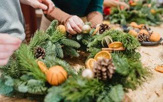 Xmas wreath on a table with two people touching it
