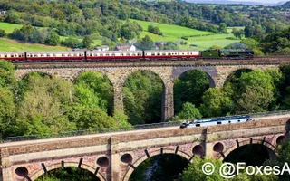 Narrowboat Silver Fox at Marple aqueduct with steam train on the nearby viaduct