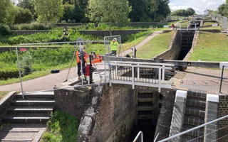Canal lock gate with fencing around it and worker standing nect to locka