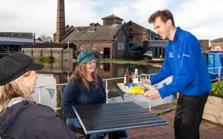 Two people on a table being handed drinks