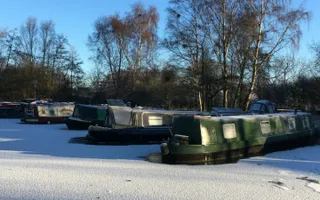 Moored boats covered in snow and surrounded by an iced-over canal