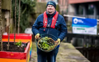 Volunteer carries planter along towpath by a lock