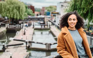 A young woman leaning on a bridge overlooking the canal