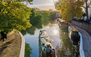 Narrowboat moving along the Regent's Canal with the sun reflecting in the water