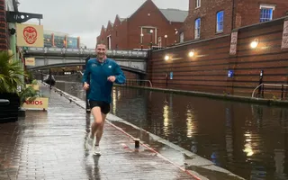 Man running along the towpath in Birmingham on a rainy day
