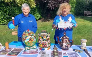 Two people wearing blue clothing holding up old canal objects to camera