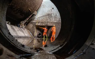 Two colleagues in high vis weld part of the wall with sparks flying.