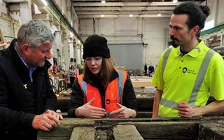 A woman and two men at work in a workshop
