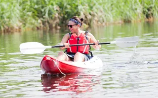 A woman paddles a canoe in the sun on the canal