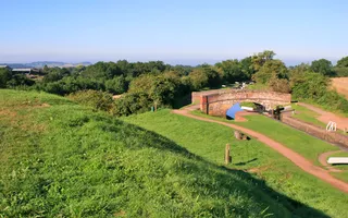 Aerial view of the a canal lock and bridge next to a field