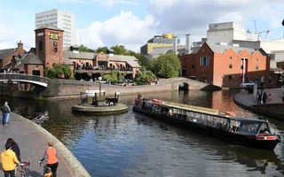 Boat turns at Birmingham Brindley Place junction, with the cityscape in the background.