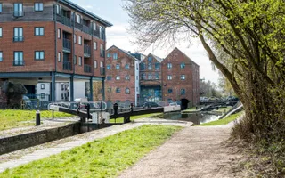 Wide shot of a canal with lock gate and residential apartments in the background