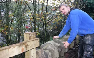 Man leaning on dry stone wall