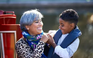 A woman smiles with a child in her arms by the canal