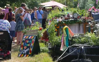 People looking at wares for sale on highly-decorated canal boats.