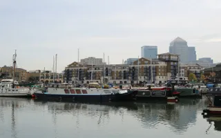 View of Limehouse Basin on Limehouse Cut with boats and flats in the foreground and skyscrapers in the background