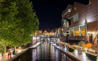 A night time scene of an urban canal with lights reflecting off the water