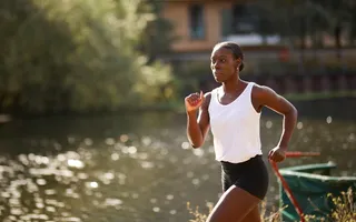 A woman running along the towpath in a white vest and black shorts